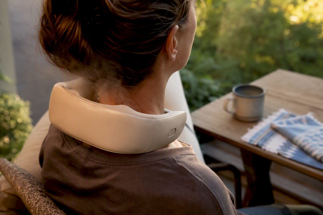 Person wearing heated neck massager at home