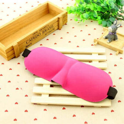 Sleep mask in bright pink color resting on a wooden surface, designed for ultimate comfort and restful sleep.