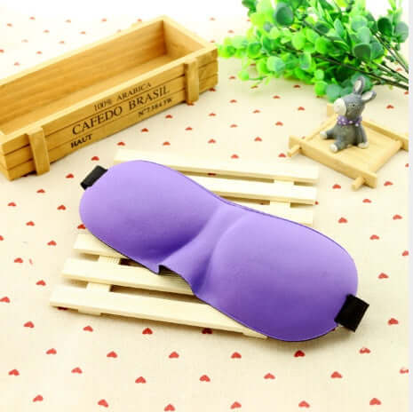 Sleep mask in purple color resting on a wooden slat, designed for ultimate comfort and restful nights.