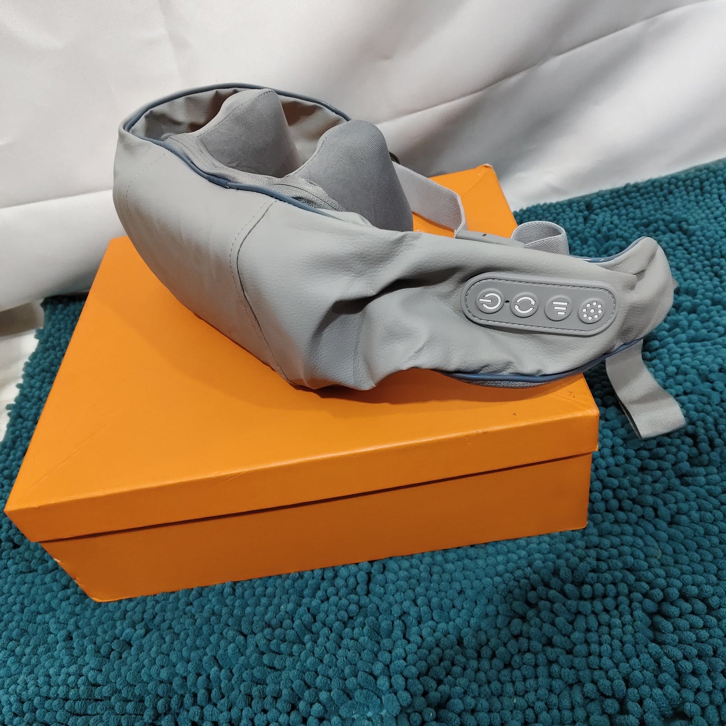 Neck Massager with Heating Mode resting on a bright orange box, designed for relaxation and tension relief.